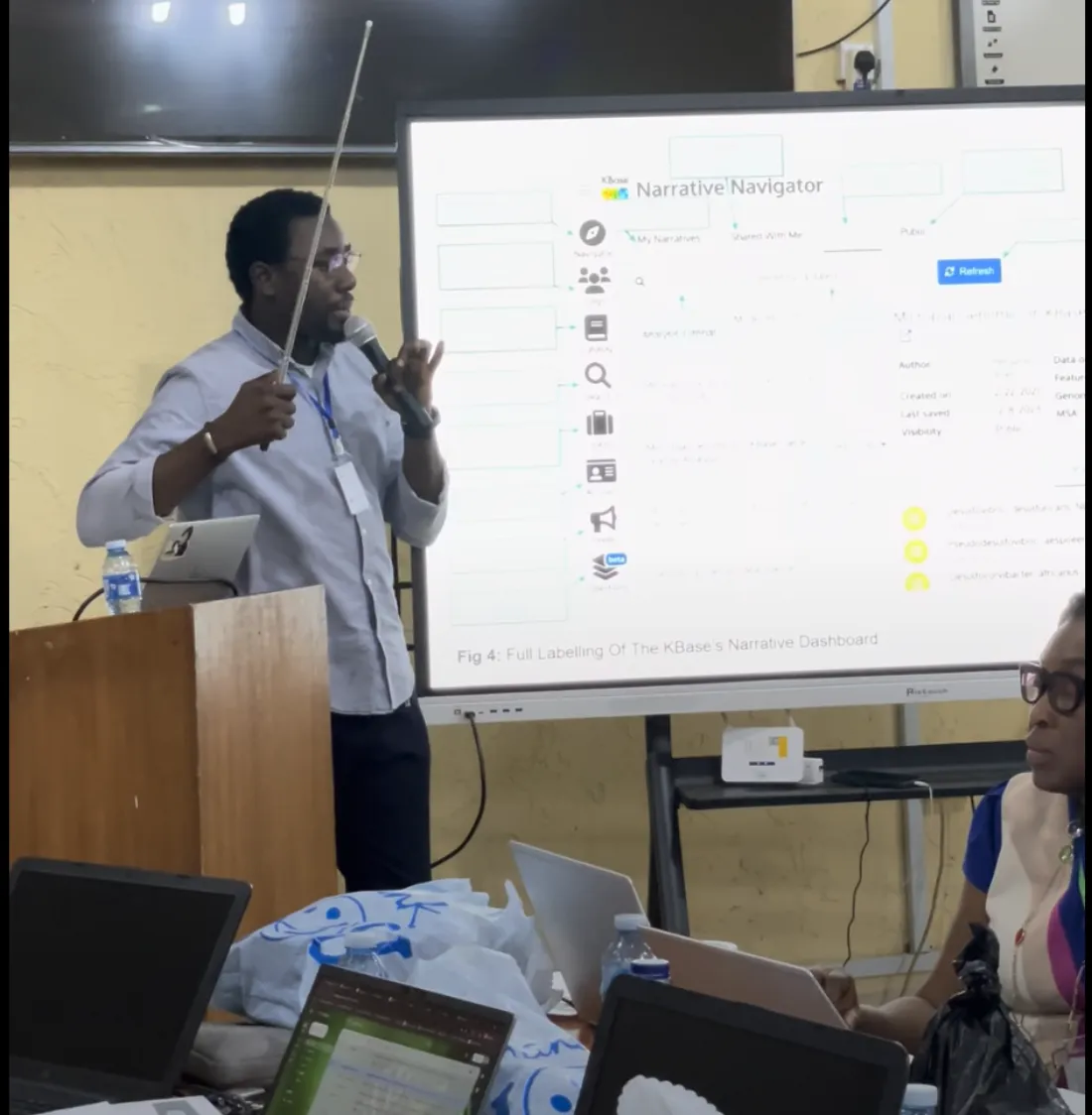 Tomiwa pointing at a labelled KBase narrative dashboard during a BioBridge 1.0 session